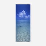A vertical panoramic image of clear blue ocean water with a detailed cloud formation in the sky above
