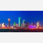 An image of the Dallas, Texas skyline at dusk featuring illuminated buildings and a clear sky.