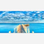 A panoramic canvas print of a wooden pier extending into a calm blue ocean with a cloudy sky above.