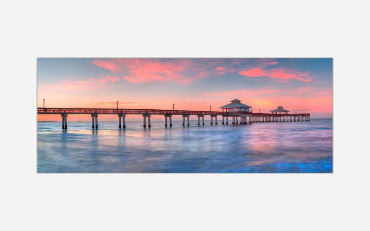 A serene image of a long pier extending into calm waters under a pastel-colored sunset sky.