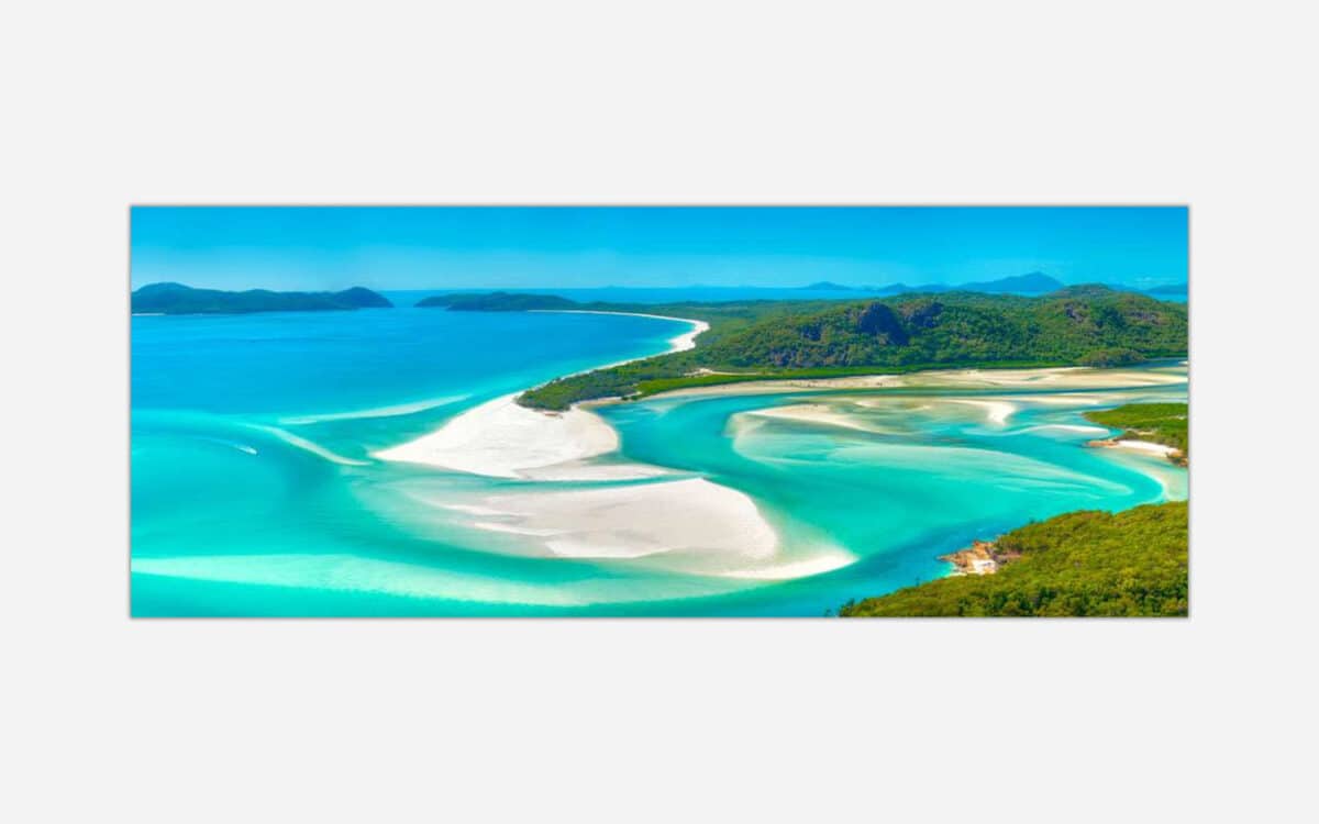 Aerial photograph of a scenic tropical beach with turquoise waters and white sand surrounded by lush greenery.