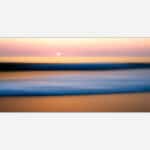 A blurred image of a beach scene at sunset with pastel colors and a tranquil ocean, creating an abstract seascape suitable for modern wall decor.