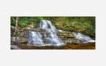 A photograph of a small, serene waterfall with silky smooth water cascading over rocks in a lush forest setting.