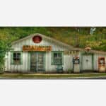 A vintage photograph of the Pink J. Plemmons Groceries & Feeds store in Luck, N.C. with old-fashioned gas pumps in front.