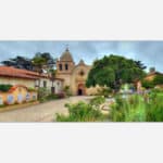 A high dynamic range (HDR) image of a historic California mission with Spanish colonial architecture surrounded by a lush garden and a fountain in the courtyard.