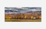 A panoramic photograph of a rustic cabin amidst a colorful autumn forest with misty mountains in the background.