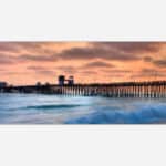 A serene sunset over a wooden ocean pier with vibrant sky colors and a calm sea.