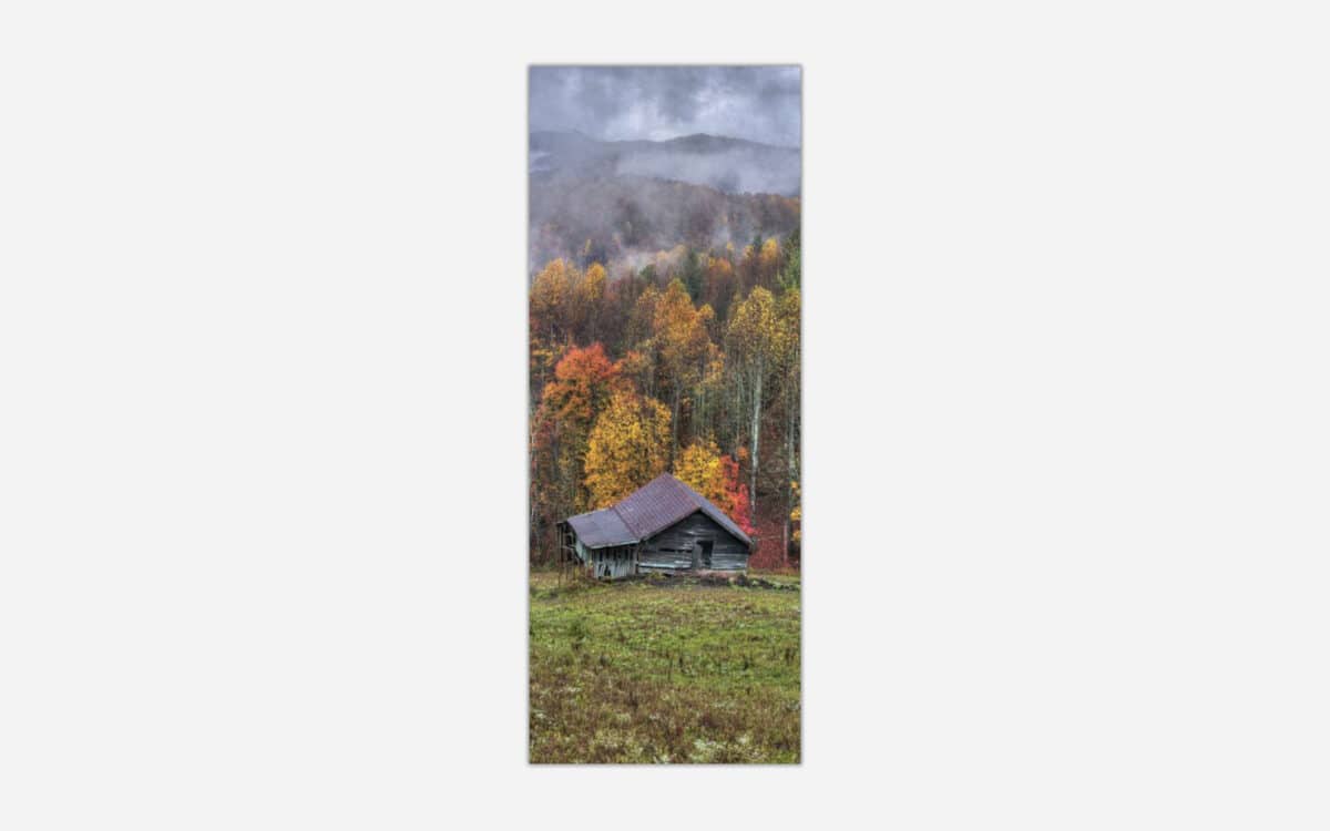 An image of a rustic cabin in a forest during autumn with vibrant fall foliage and misty mountains in the background.