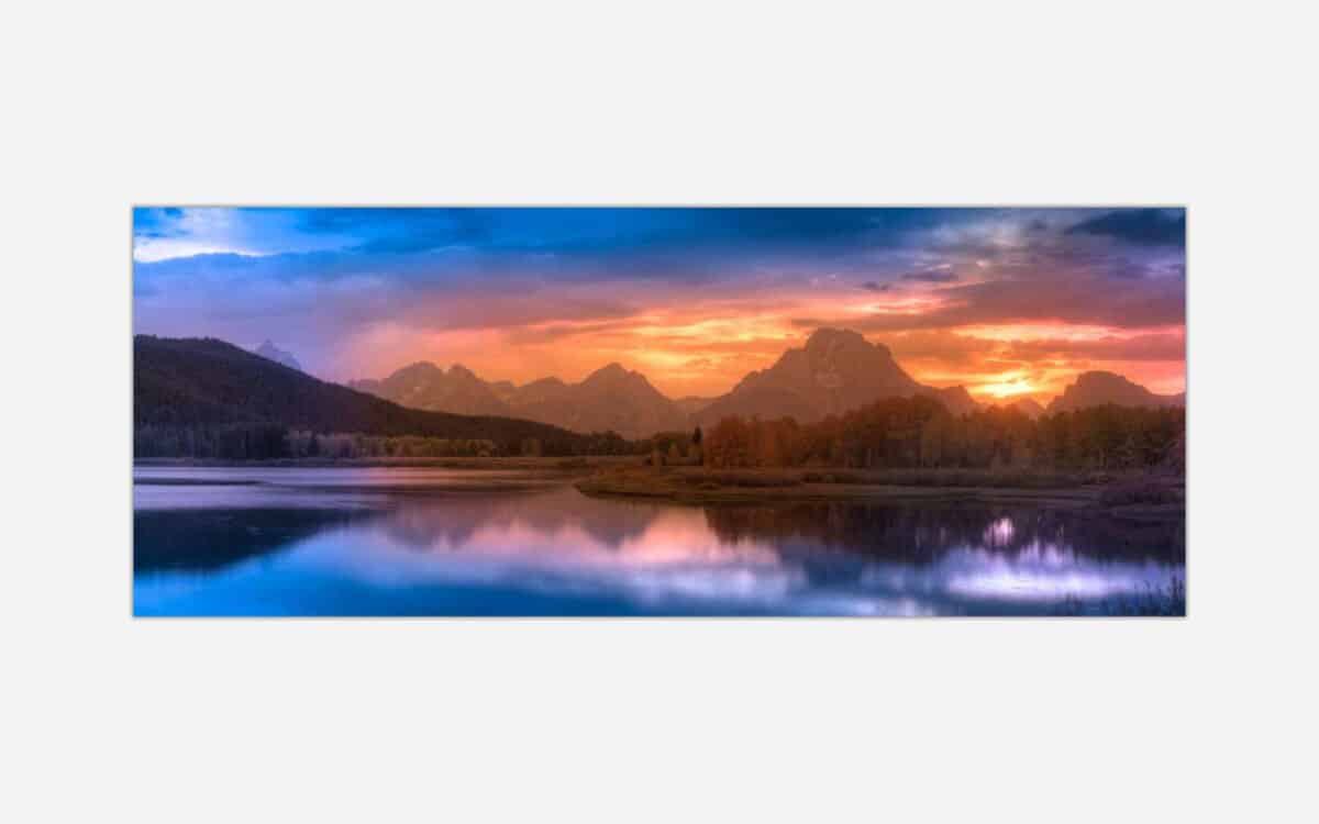 A serene mountain landscape at sunset with vibrant colors in the sky reflecting on a calm lake.
