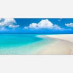 A panoramic canvas print of a tranquil tropical beach with vivid turquoise sea, white sand, and a clear blue sky with fluffy clouds.