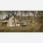 A rustic image of an old abandoned house with a vintage green truck parked outside, surrounded by a barren countryside landscape.