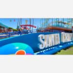 A colorful image of Santa Cruz Beach Boardwalk with clear blue skies and amusement park attractions in the background.