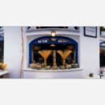 An artistic photograph of a charming Italian pizzeria with blue window frames, displayed pasta, and a traditional Mediterranean aesthetic.