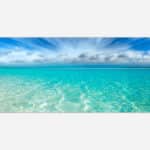 A canvas print featuring a serene tropical beach scene with clear turquoise water and a blue sky with scattered clouds.