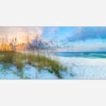 A panoramic wall art piece featuring a serene beach at sunset with ocean waves, fluffy clouds, and beach grass in the sand dunes.