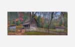 An image of an old wooden cabin surrounded by a rustic fence amidst trees with autumn foliage.