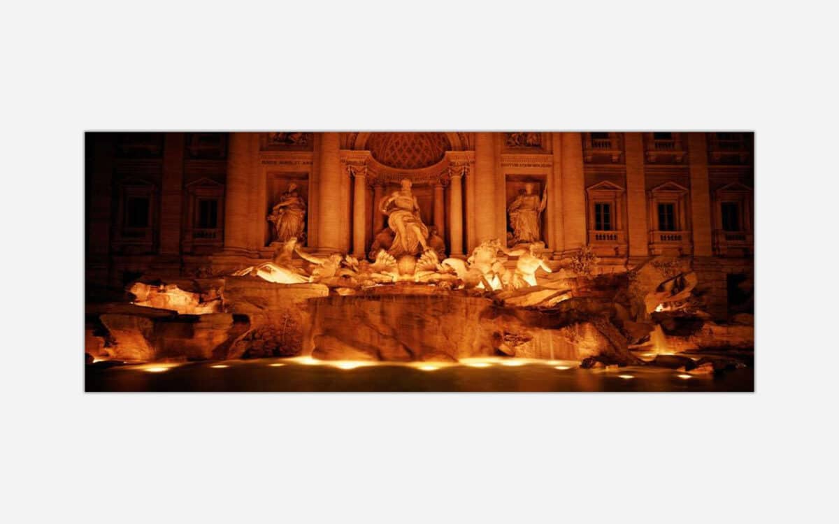 A nighttime photograph of the illuminated Trevi Fountain in Rome, showcasing its baroque sculptures and architecture.
